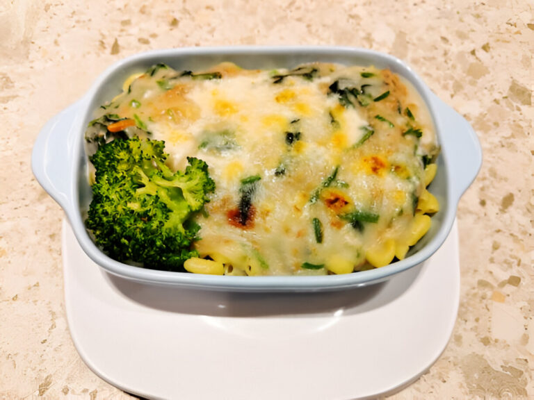 A creamy pasta bake with broccoli in a light blue dish