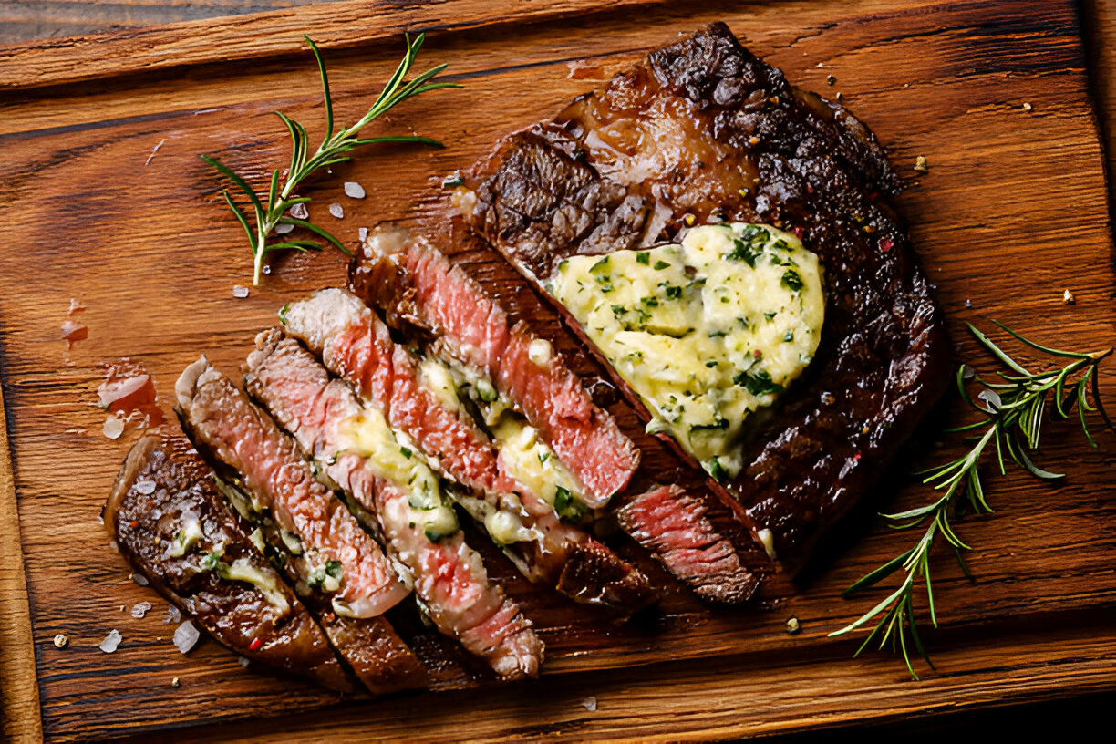 A perfectly cooked steak sliced on a wooden board, topped with herb butter and garnished with fresh rosemary