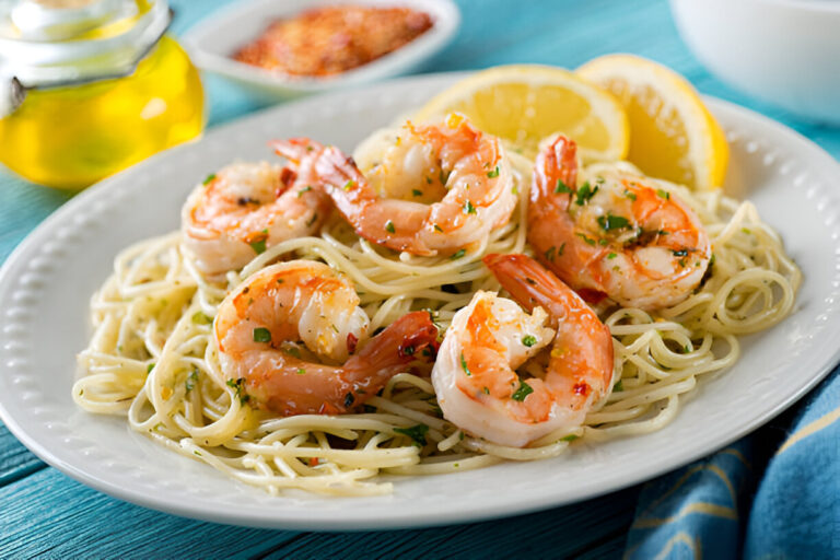 A plate of shrimp pasta with lemon slices and parsley, garnished with olive oil on a blue wooden table.