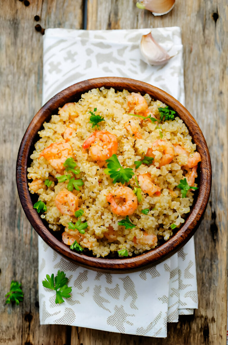 A wooden bowl of quinoa mixed with shrimp and garnished with fresh parsley, placed on a decorative napkin.